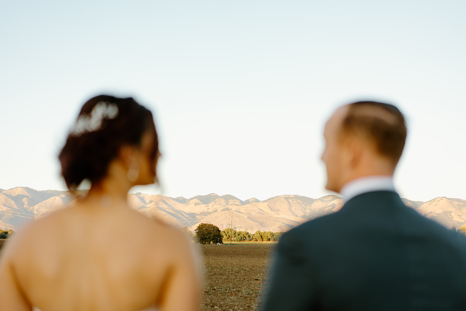 Bride and groom look at the mountains at The White Barn in San Luis Obispo CA, photography by Cobblestone
